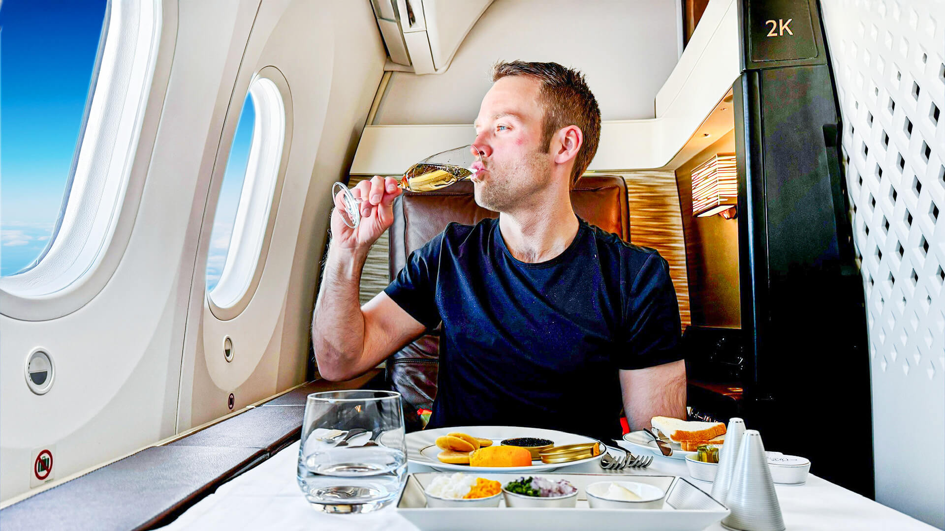 Nik sitting in first class eating a delicious dinner and drinking champagne on an Etihad flight