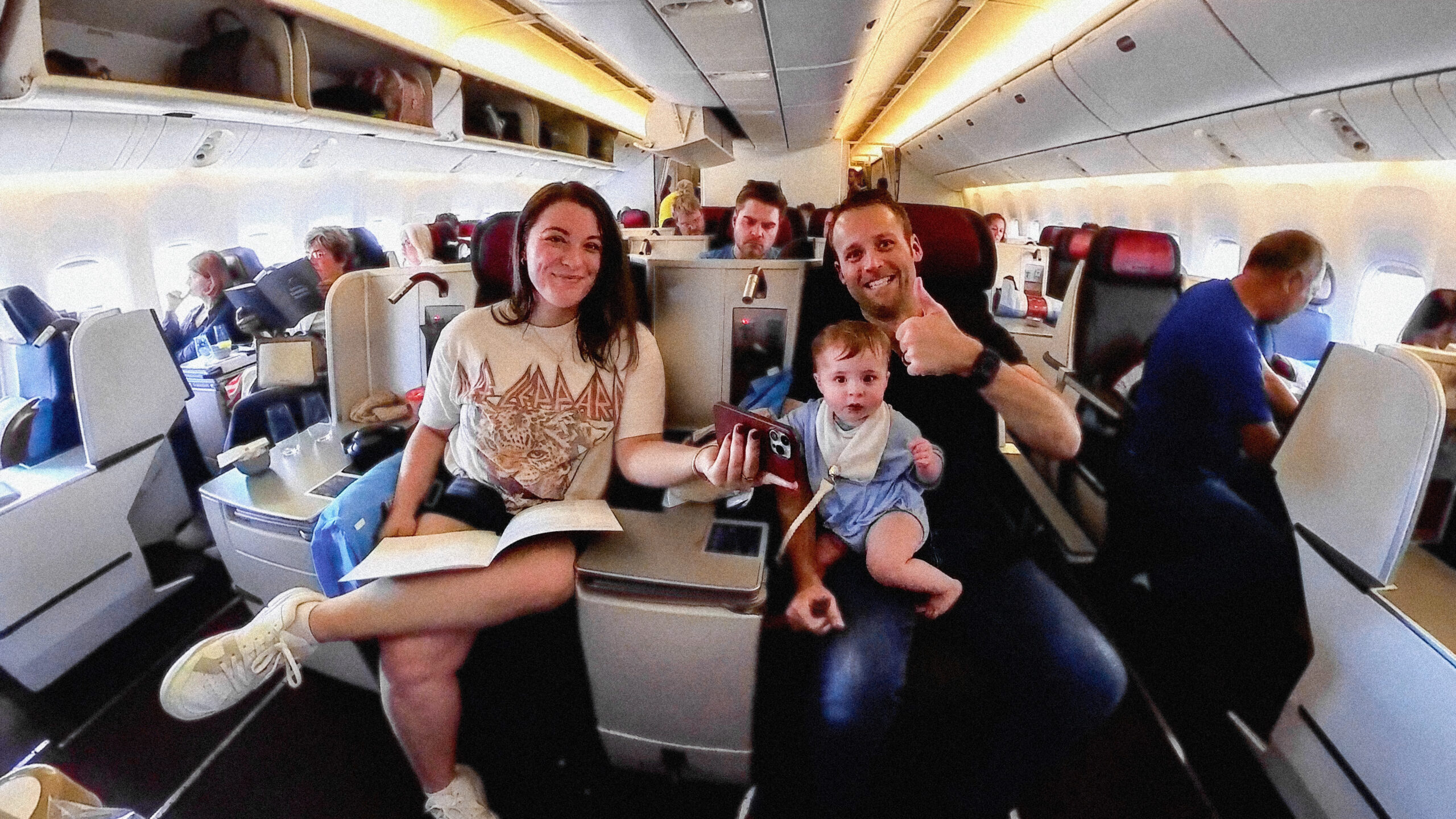 Nik, Allie and their child sitting in an airplane smiling