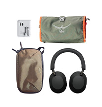 Flat lay of travel gear in a packing list ,headphones, travel charger, and toiletry bag